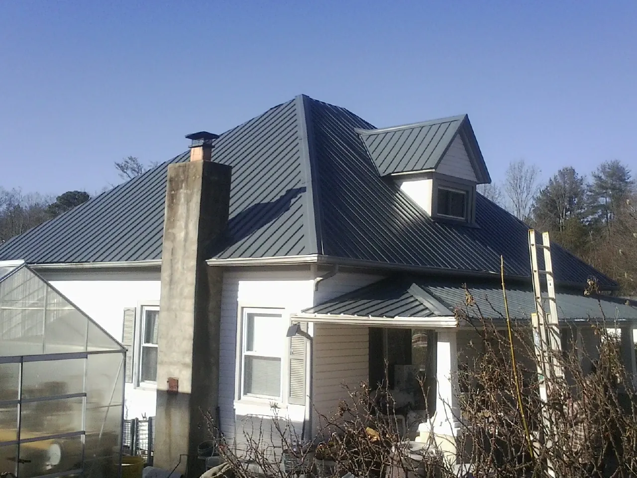 Dark blue standing seam metal roof on a white farmhouse with dormer — Slate & Tile Roof Repair by Roofing Brothers in Westmont