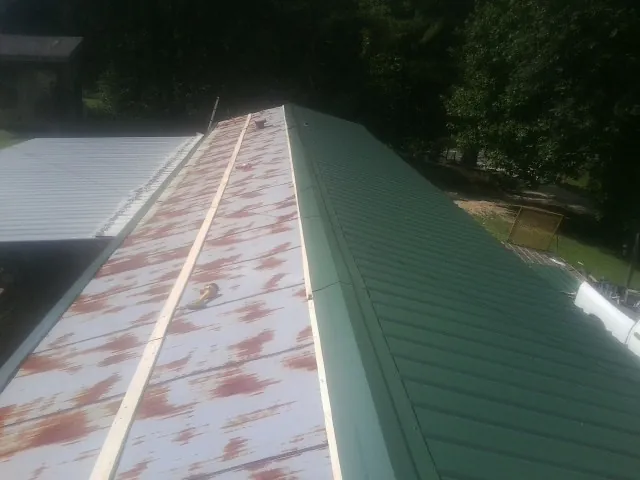 Old rusted panels beside newly installed green metal roofing — Wind Damage Roof Repair by Roofing Brothers in Westmont