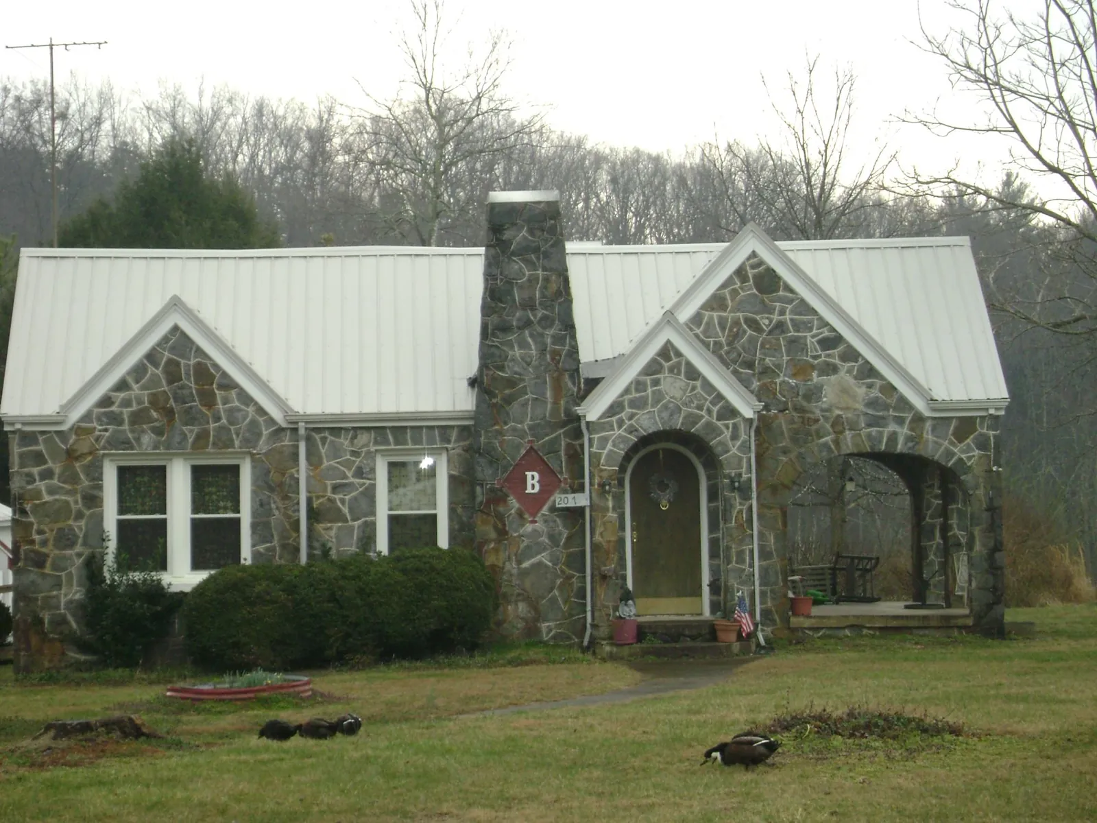 White metal roof on a stone cottage with steep gables in Westmont