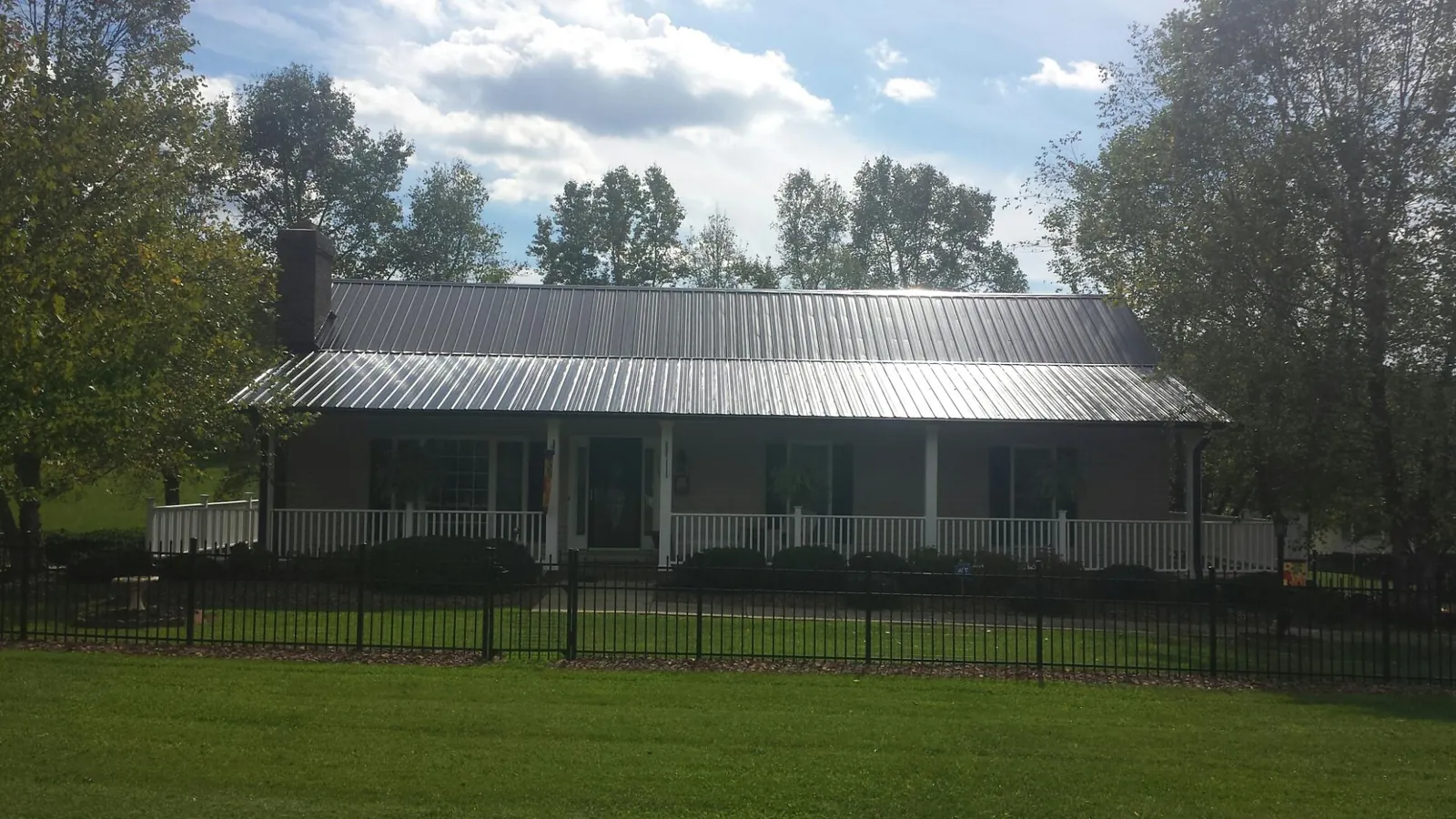 Gray metal roof on a brick ranch with a full width front porch — Gutter Guard Installation work by our crew in Westmont