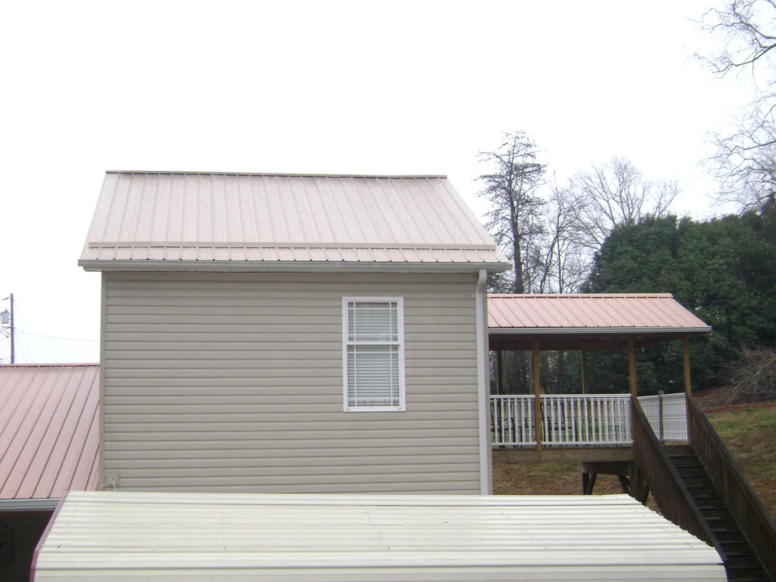 Tan metal roofs on a two story addition and attached porch, from a Roof Replacement job in Westmont