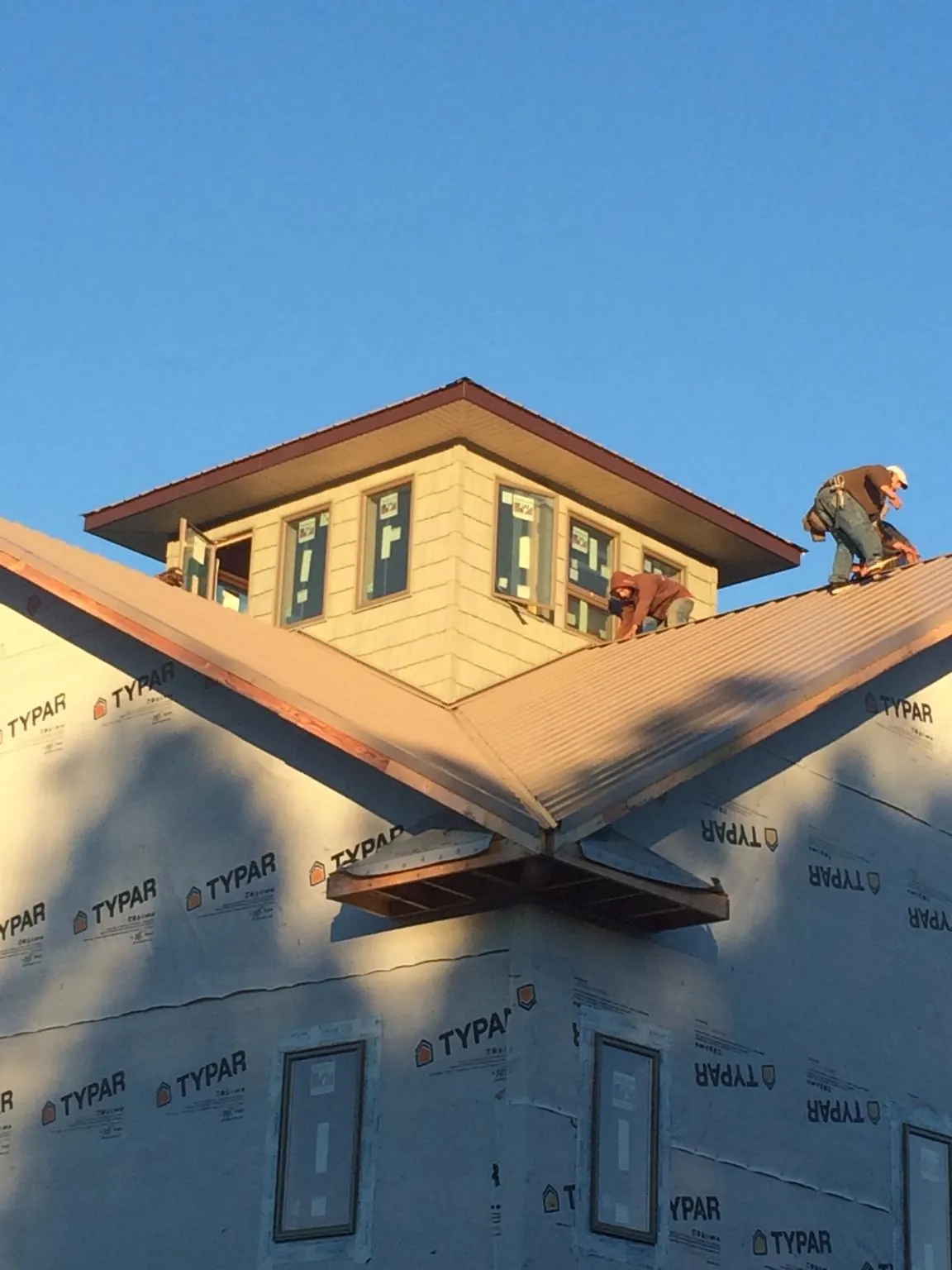 Roofers working around a rooftop cupola on a new metal roof at sunset — Roof Waterproofing in Westmont by Roofing Brothers